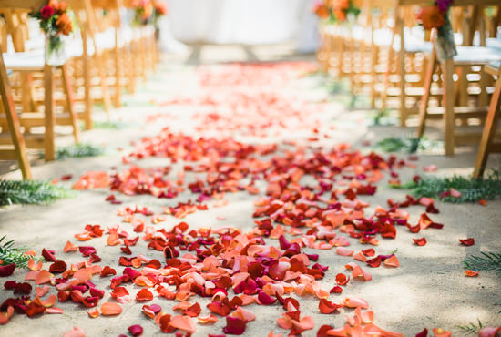 Red flower petals cover the aisle of a beautiful and colorful wedding ceremony at the Santa Barbara Historical Museum